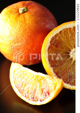 Blood orange photographed against a black background 115229693