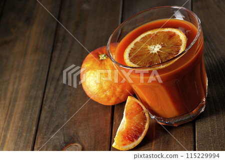 Blood orange juice with slices of fruit floating in it 115229994