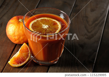 Blood orange juice with slices of fruit floating in it 115229995