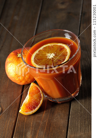 Blood orange juice with slices of fruit floating in it 115230001
