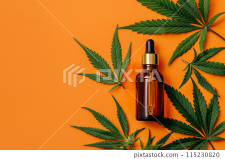 dropper bottle with CBD oil and green cannabis leaves on orange background 115230820