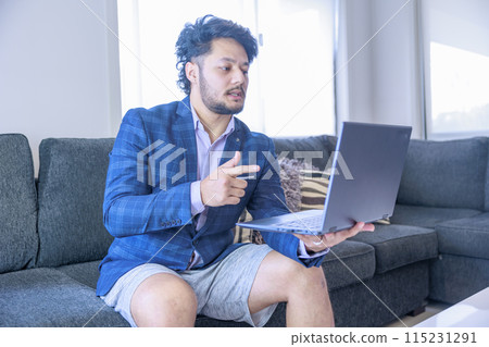 A man wearing only a suit on his upper body participating in an online meeting A man wearing only a suit on his upper body participating in an online meeting 115231291