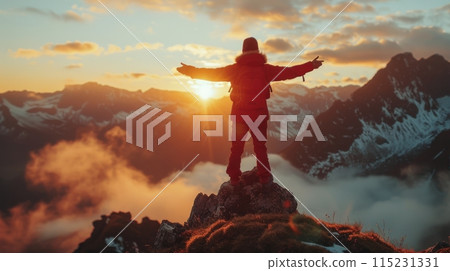 Adventurer Standing on Mountain Peak at Sunset With Arms Outstretched 115231331