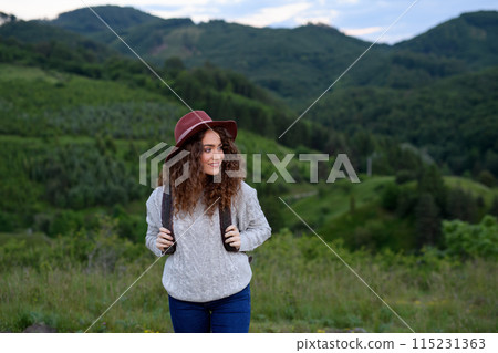 Young tourist woman traveller with backpack walking in nature. Active hiker on trail in mountains enjoying sunset. Young tourist woman traveller with backpack walking in nature. Active hiker on trail in mountains enjoying sunset. 115231363
