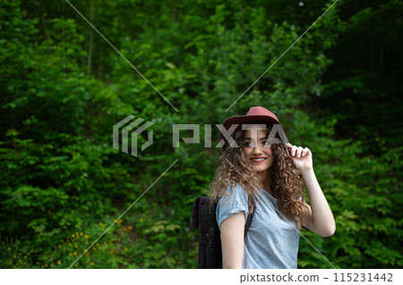 Young tourist woman traveller with backpack walking in nature. Active female hiker on trail in woods. Young tourist woman traveller with backpack walking in nature. Active female hiker on trail in woods. 115231442