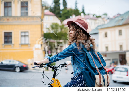 Female traveller on electric scooter in small city, sightseeing. Young tourist using bike during her summer solo trip, vacation. 115231502