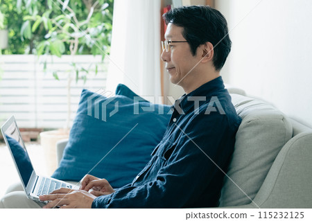 man using computer on sofa 115232125