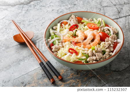 Thai Yum Mama salad with instant noodles, shrimp, minced pork, tomatoes, herbs, celery and onions close-up in a bowl. Horizontal Thai Yum Mama salad with instant noodles, shrimp, minced pork, tomatoes, herbs, celery and onions close-up in a bowl. Horizontal 115232307