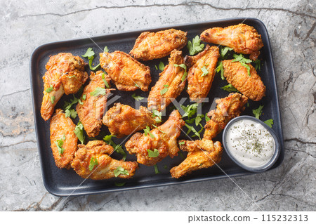 Spicy crispy baked chicken wings breaded with curry close-up in a plate. Horizontal top view 115232313