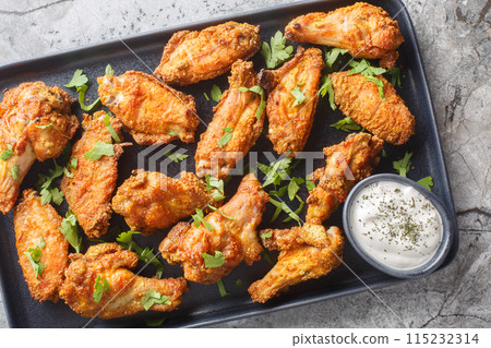 Tasty Baked Curry Chicken Wings served with greek yogurt closeup on the plate. Horizontal top view 115232314