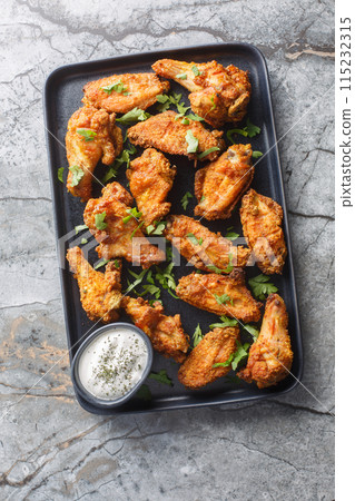 Crispy baked curry-breaded chicken wings close-up in a plate. Vertical top view 115232315