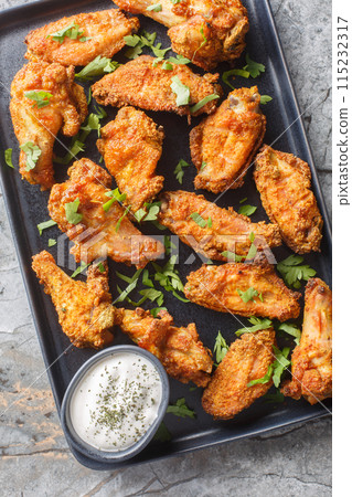 Crispy Curry Chicken Wings served with greek yogurt closeup on the plate. Vertical top view 115232317