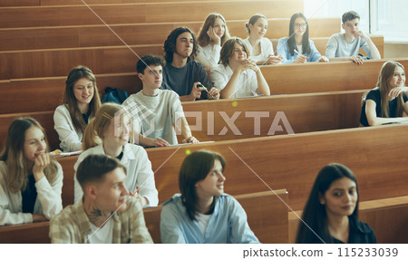 Young people, boys and girls, students sitting in university classroom, attending lessons, listening to teacher. Multiethnic group. 115233039