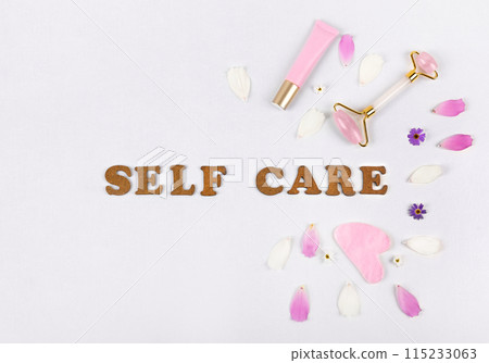 Pink jade roller, gua sha for face massage and cream or gel for face with pink and white flower petals. Facial massager tools. Anti age, lifting and toning care. Modern selfcare concept. Pink jade roller, gua sha for face massage and cream or gel for face with pink and white flower petals. Facial massager tools. Anti age, lifting and toning care. Modern selfcare concept. 115233063