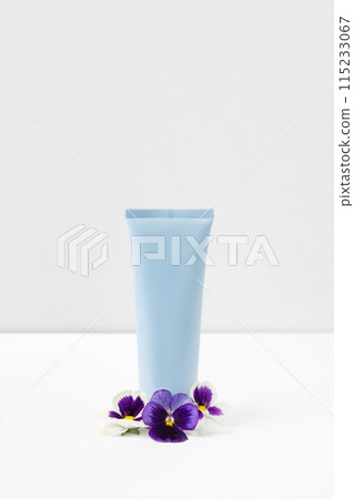 Cosmetic bottle container with purple and white viola. Top view of mockup of blue bottle plastic tube for branding of cosmetics gel, cream, skin care. 115233067