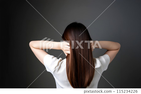 A gloomy woman with her back facing away from the camera, holding the back of her head 115234226