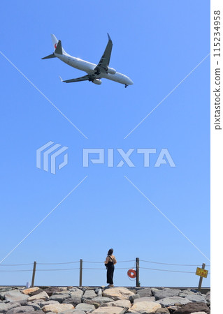 一位女士抬頭看著飛機，降落在羽田機場 115234958