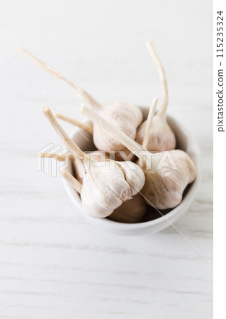 Ripe organic garlic clove and bulb on white wooden background.  Close-up. Selective focus. 115235324