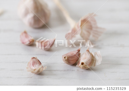 Ripe organic garlic clove and bulb on white wooden background.  Close-up. Selective focus. 115235329