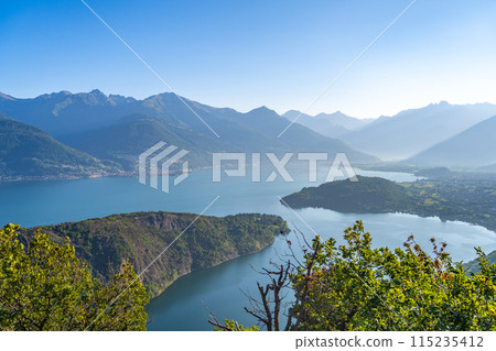 A beautiful mountain range with a lake in the foreground. The lake is calm and the mountains are covered in trees. The sky is clear and the sun is shining brightly. The scene is peaceful and serene A beautiful mountain range with a lake in the foreground. The lake is calm and the mountains are covered in trees. The sky is clear and the sun is shining brightly. The scene is peaceful and serene 115235412