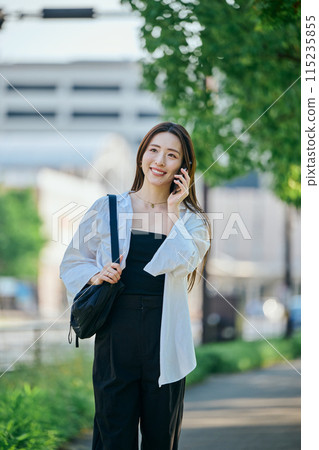 A young woman walking while talking on her smartphone 115235855
