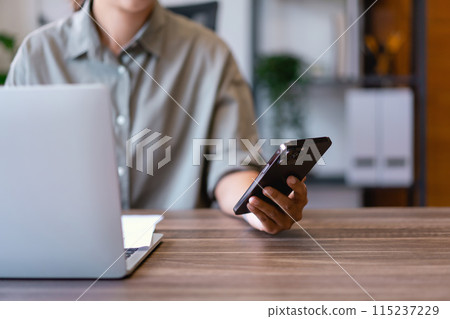 Casual business women reading finance paper and checking data on phone to analysis market strategy 115237229