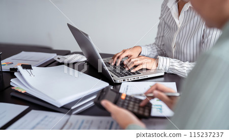 Two business real estate seller using calculator to calculating and discussion about property investment while typing terms data about home sales contract and home insurance on laptop in office Two business real estate seller using calculator to calculating and discussion about property investment while typing terms data about home sales contract and home insurance on laptop in office 115237237