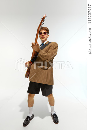 Deep connection to music. Young talented man, electric bass guitarist performing against white studio background. 115237957