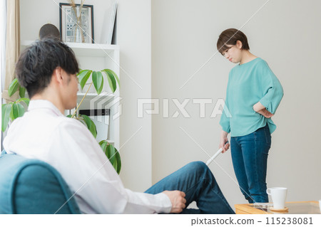 A woman cleaning and a man using a smartphone A woman cleaning and a man using a smartphone 115238081