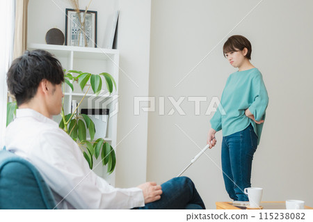 A woman cleaning and a man using a smartphone A woman cleaning and a man using a smartphone 115238082