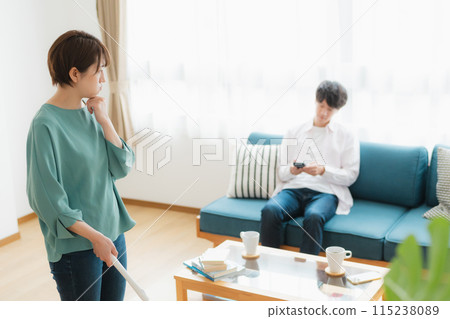 A woman cleaning and a man using a smartphone 115238089