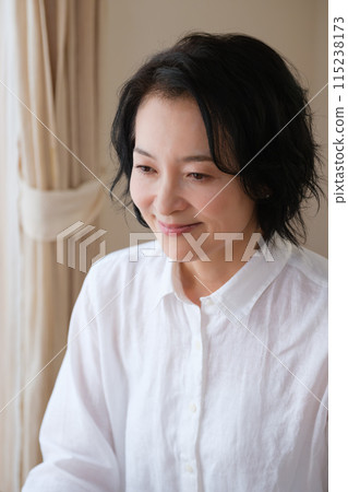 A middle-aged woman writing a letter to her family in the living room 115238173