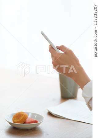 中年婦女在客廳用智慧型手機搜尋資訊並做筆記 中年婦女在客廳用智慧型手機搜尋資訊並做筆記 115238207