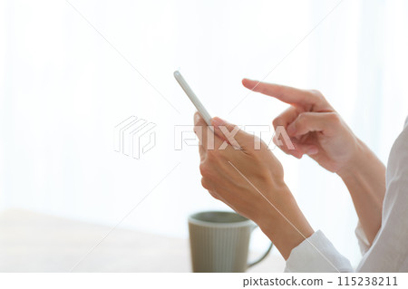 中年婦女在客廳用智慧型手機搜尋資訊並做筆記 115238211