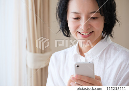 中年婦女在客廳用智慧型手機搜尋資訊並做筆記 115238231