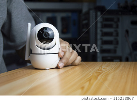 White ip camera lies on wooden floor, man using ip camera White ip camera lies on wooden floor, man using ip camera 115238867