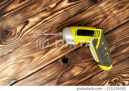 a cordless screwdriver. Cordless drill on a wooden background. DIY concept 115239385