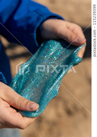 Close-up of a boy holding slime on a sunny day Close-up of a boy holding slime on a sunny day 115239399