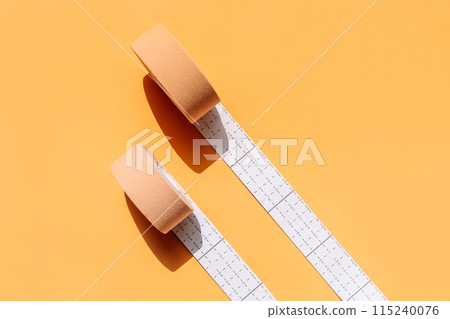 Adhesive tapes for the face in rolls on a yellow background, hard light 115240076