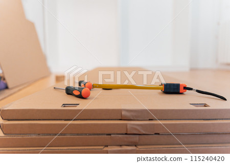 New furniture wrapped in cardboard stacked in the room with tools on top 115240420