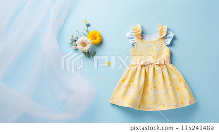 yellow baby dress with ruffled sleeves and a bow, displayed on a pastel blue background 115241489