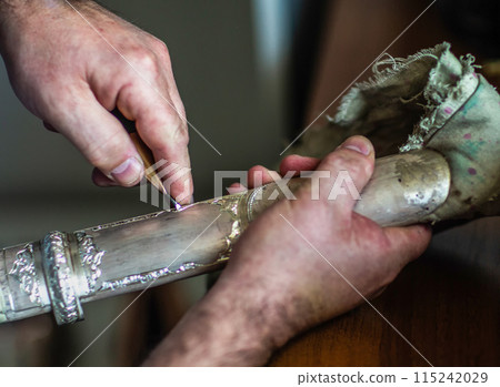 The hands of a dagger maker at work, close-up. 115242029