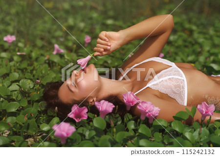 Sensual Woman in White Lingerie Enjoying Flowers in a Lush Green Field Sensual Woman in White Lingerie Enjoying Flowers in a Lush Green Field 115242132