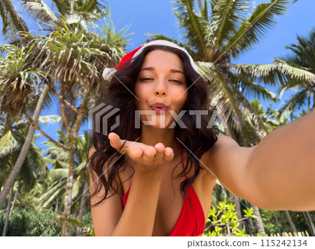 Woman in Santa Hat Blowing Kiss on Tropical Beach 115242134
