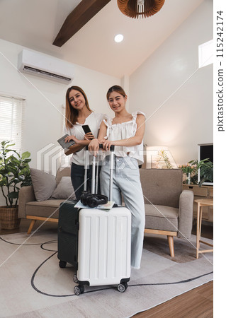 Two Young Women Preparing for Travel with Suitcases Indoors, Concept of Friendship and Summer Travel Two Young Women Preparing for Travel with Suitcases Indoors, Concept of Friendship and Summer Travel 115242174