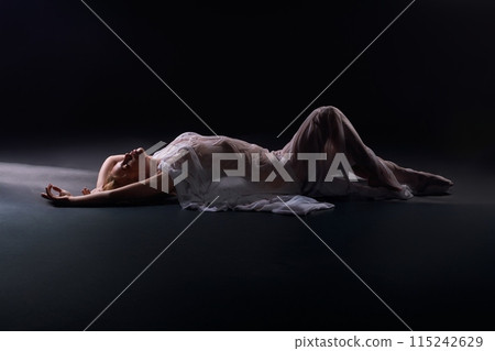 Unrecognizable naked woman silhouette laying in white fabric 115242629