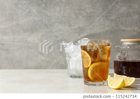 A glass of cold tea with ice and an orange 115242734
