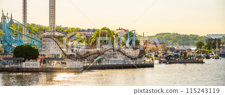 The sun rises on Grona Lund, Stockholms waterfront amusement park, casting a warm glow over the thrill rides and serene waters. 115243119