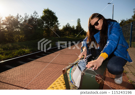 Teenagers spilled the contents of a travel suitcase on the train platform. An unfastened travel suitcase. Adventure on the platform. 115243196