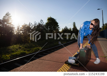 Teenagers spilled the contents of a travel suitcase on the train platform. An unfastened travel suitcase. Adventure on the platform. 115243199
